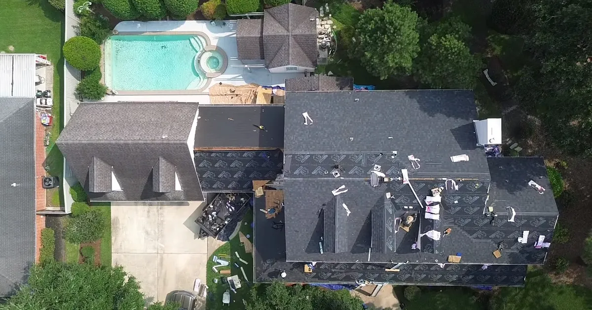 Aerial view of roof replacement in progress with crew installing new shingles, Baytown TX