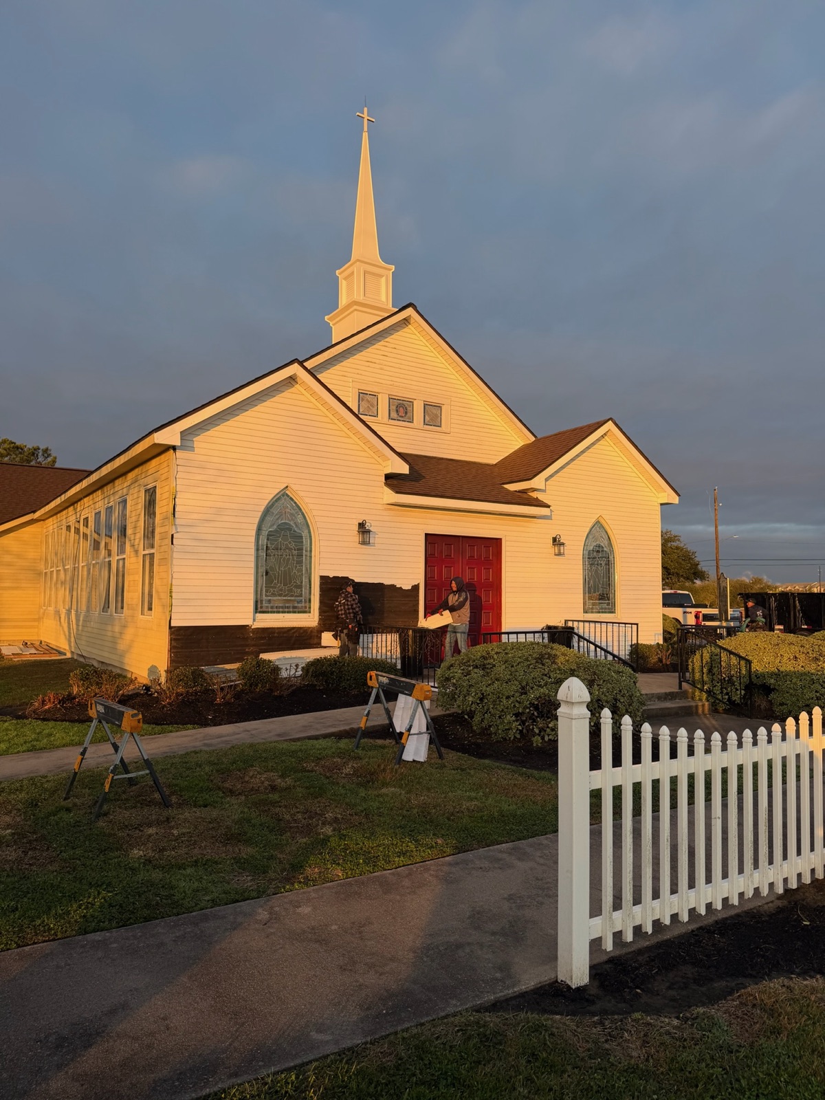 Crew staging ladders and materials during church exterior restoration